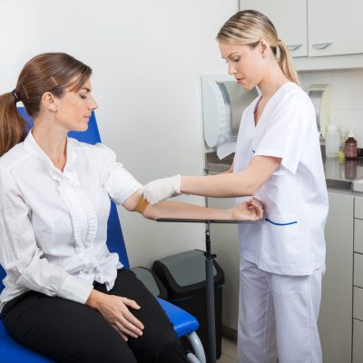 Nurse preparing businesswoman for blood test in hospital